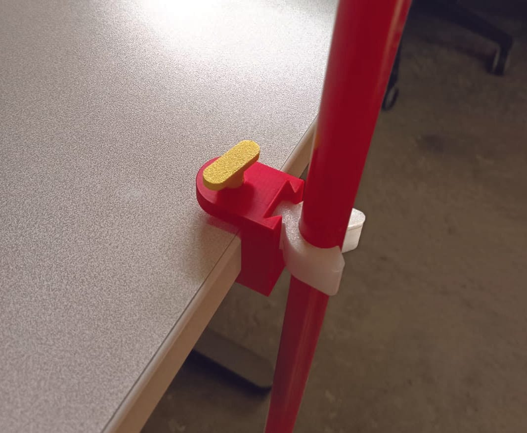 Le porte-canne serré sur le bord d'une table, une béquille rouge maintenue par l'anneau souple